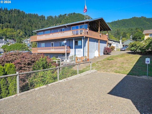 rear view of house featuring a mountain view, a view of trees, and a balcony