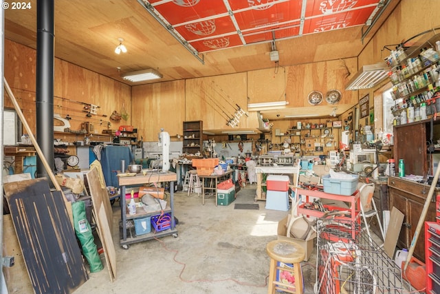 interior space featuring concrete flooring, wood walls, and a workshop area