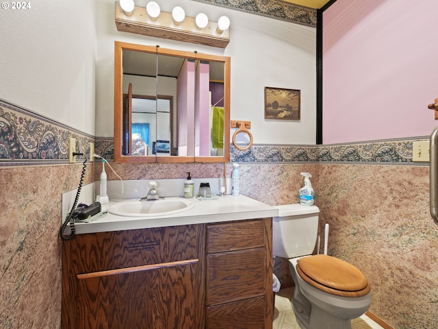 half bathroom featuring a wainscoted wall, toilet, tile walls, and vanity