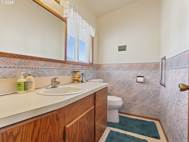 bathroom with vanity, tile walls, a wainscoted wall, toilet, and tile patterned floors