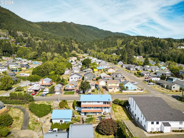 aerial view of residential area featuring a forest and a mountainous background