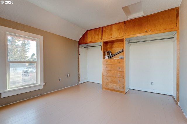 unfurnished bedroom with lofted ceiling, light hardwood / wood-style flooring, and a closet