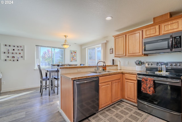 kitchen with kitchen peninsula, stainless steel appliances, plenty of natural light, and sink