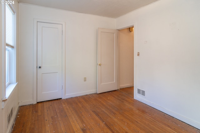 unfurnished bedroom with wood-type flooring and multiple windows