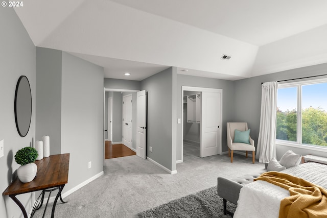 bedroom with vaulted ceiling, a walk in closet, light colored carpet, and a closet