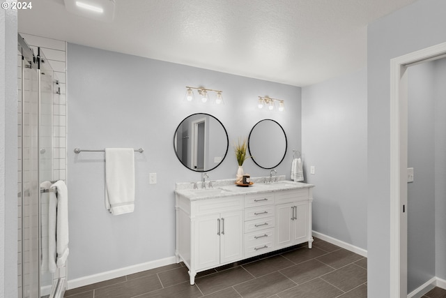 bathroom with vanity, a shower with shower door, and a textured ceiling