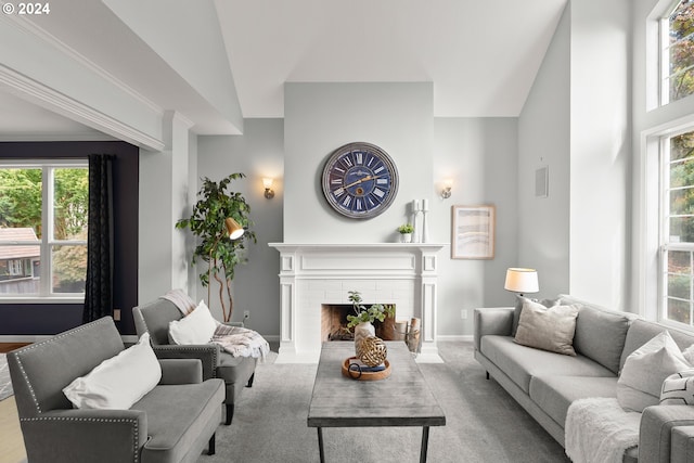 carpeted living room with a wealth of natural light, lofted ceiling, and a brick fireplace