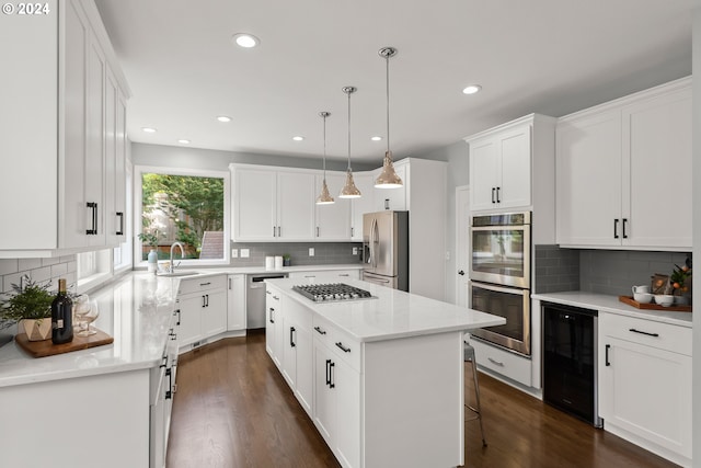 kitchen with appliances with stainless steel finishes, a kitchen island, pendant lighting, white cabinets, and wine cooler