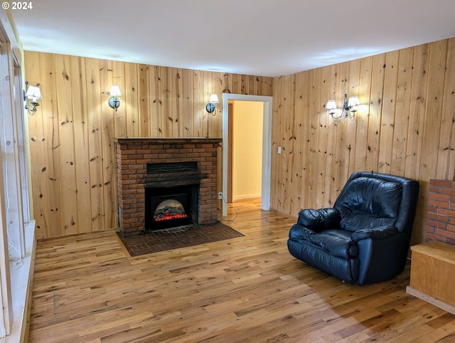 sitting room with hardwood / wood-style floors, wooden walls, and a fireplace