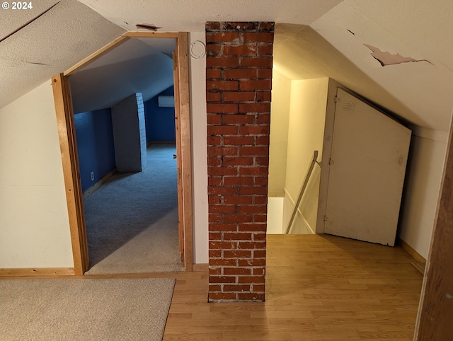 additional living space featuring light wood-type flooring, vaulted ceiling, and a textured ceiling