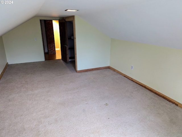 additional living space featuring vaulted ceiling and light colored carpet