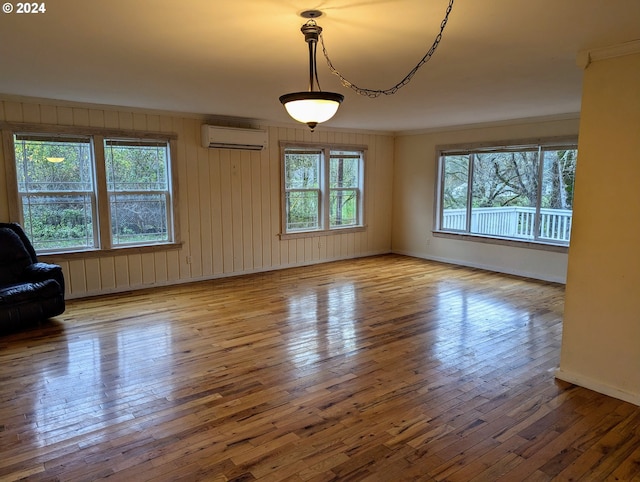 interior space featuring a wall mounted air conditioner, hardwood / wood-style floors, and crown molding