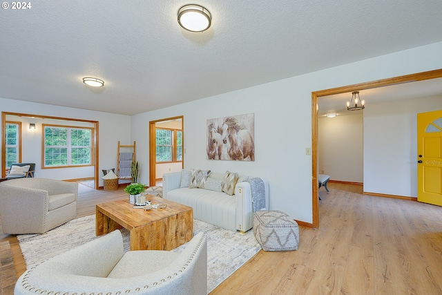 living room with a textured ceiling, an inviting chandelier, and light hardwood / wood-style flooring