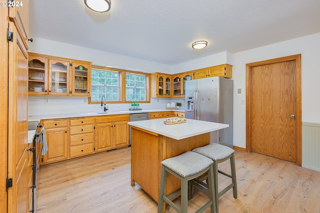 kitchen featuring a center island, stainless steel appliances, light hardwood / wood-style floors, sink, and a breakfast bar area