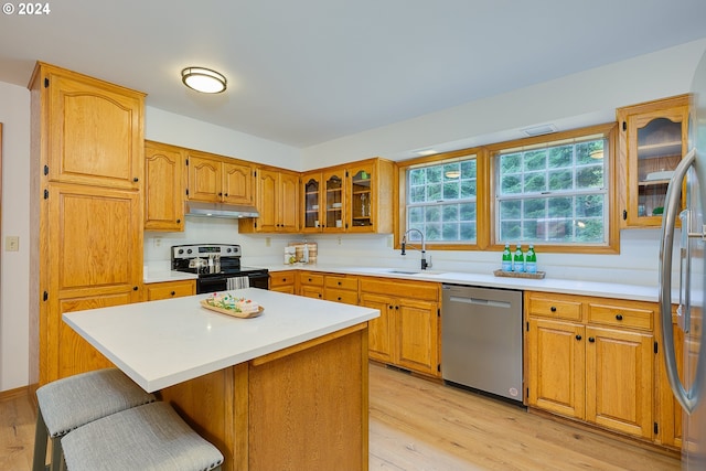 kitchen featuring appliances with stainless steel finishes, sink, light hardwood / wood-style floors, and a center island