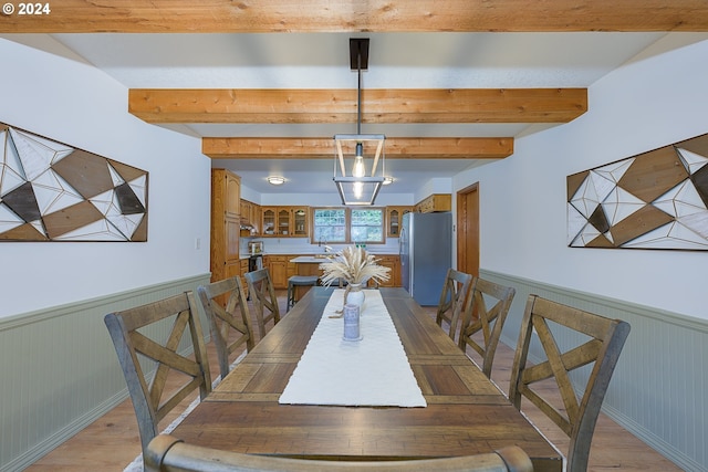 dining space with light hardwood / wood-style flooring and beamed ceiling