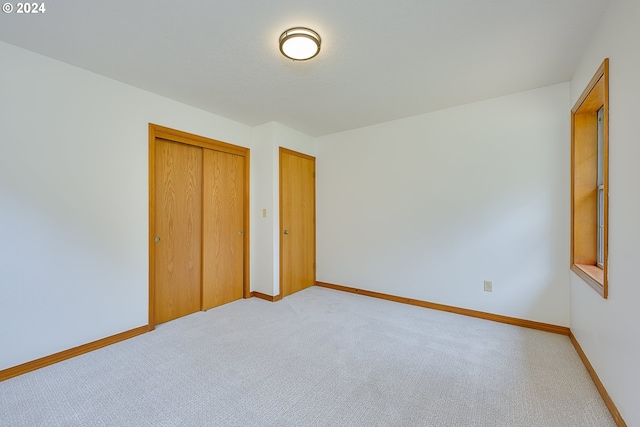 unfurnished bedroom with light colored carpet and a closet