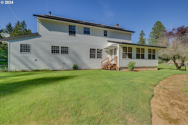 rear view of property featuring a lawn