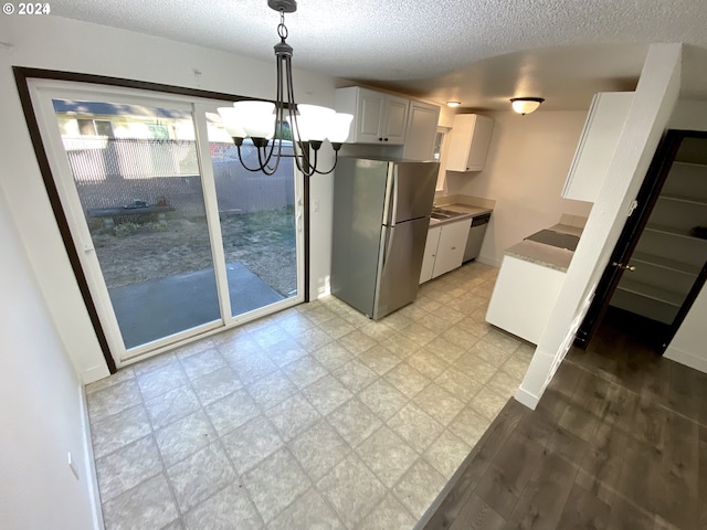 kitchen with an inviting chandelier, decorative light fixtures, white cabinetry, stainless steel appliances, and a textured ceiling