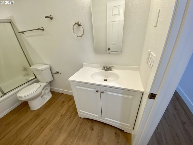 full bathroom featuring vanity, toilet, combined bath / shower with glass door, and hardwood / wood-style floors