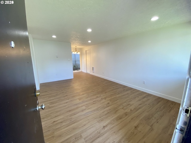 unfurnished room featuring wood-type flooring, a textured ceiling, and a notable chandelier