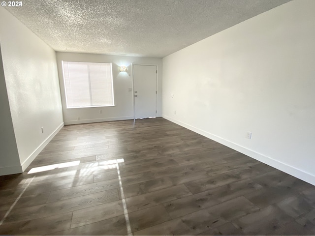 empty room with dark wood-type flooring and a textured ceiling