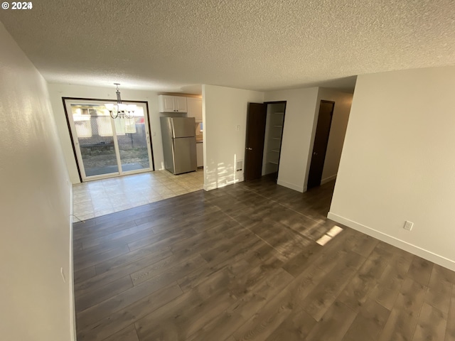 empty room with dark hardwood / wood-style floors, a chandelier, and a textured ceiling