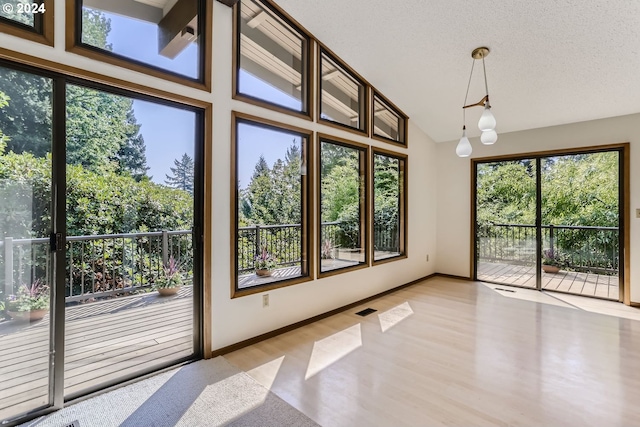 unfurnished room featuring high vaulted ceiling, light hardwood / wood-style floors, and a textured ceiling