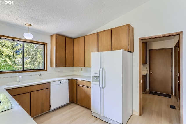 kitchen featuring light hardwood / wood-style floors, a textured ceiling, white appliances, and sink