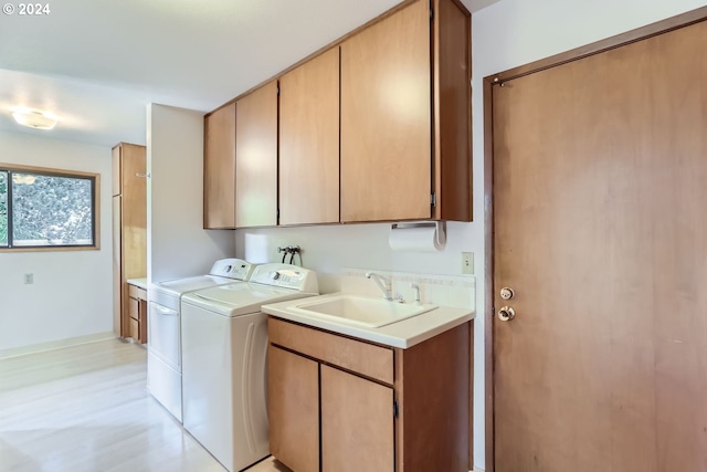 laundry room featuring cabinets, washer and clothes dryer, and sink