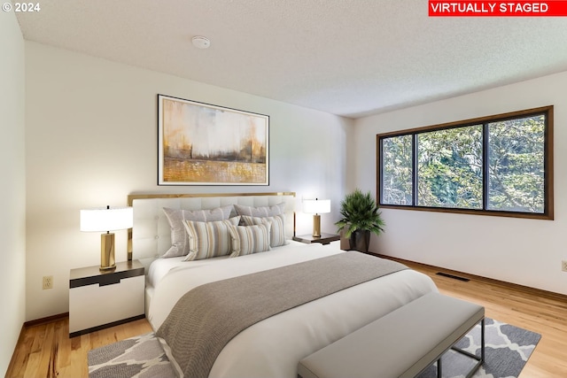 bedroom with a textured ceiling and light hardwood / wood-style flooring