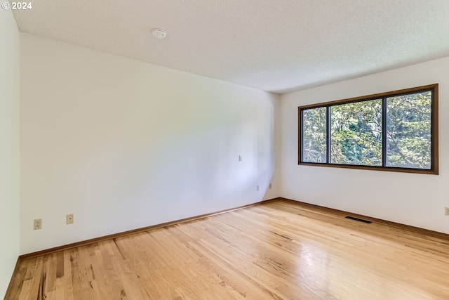 unfurnished room featuring light wood-type flooring and a textured ceiling