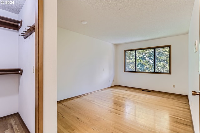 spare room with a textured ceiling and light hardwood / wood-style flooring