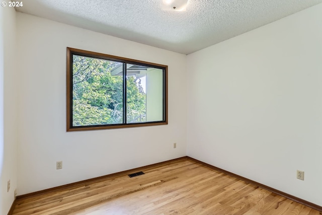 unfurnished room featuring a textured ceiling and light wood-type flooring