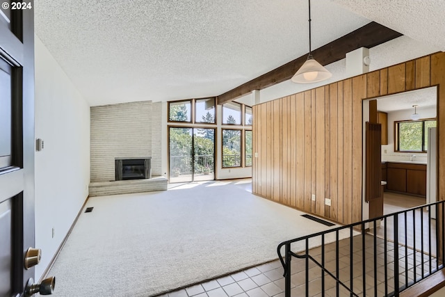 unfurnished living room featuring a textured ceiling, a healthy amount of sunlight, carpet, and a large fireplace