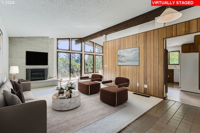 living room featuring a large fireplace, vaulted ceiling with beams, a textured ceiling, and dark hardwood / wood-style floors