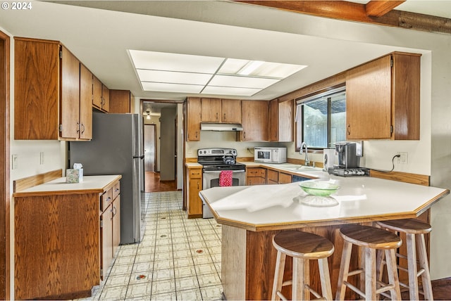 kitchen featuring a kitchen bar, kitchen peninsula, sink, and appliances with stainless steel finishes