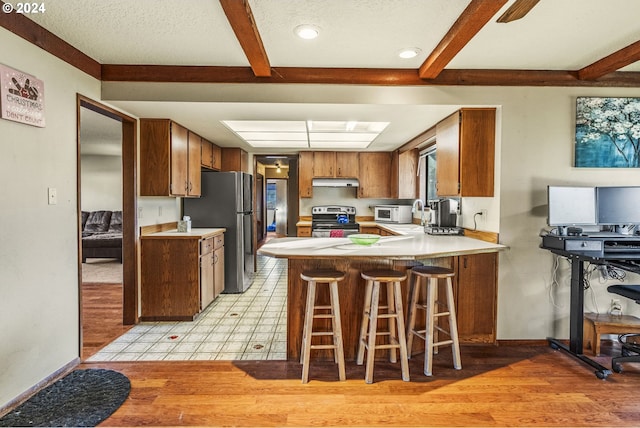 kitchen with a kitchen bar, kitchen peninsula, stainless steel appliances, and light wood-type flooring