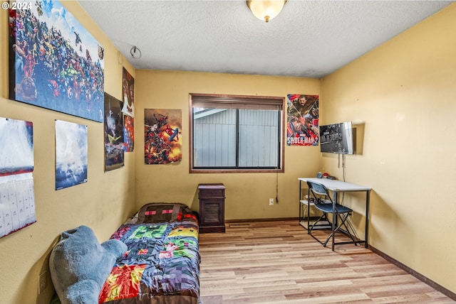 bedroom with a textured ceiling and light hardwood / wood-style flooring