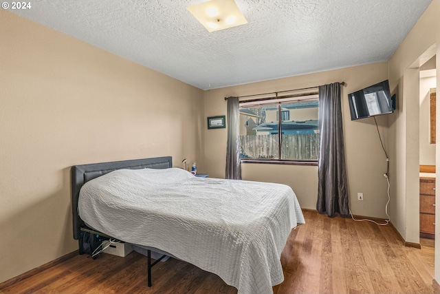 bedroom featuring a textured ceiling and light hardwood / wood-style flooring