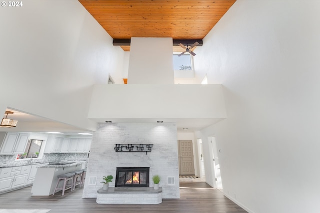 unfurnished living room with plenty of natural light, hardwood / wood-style floors, wooden ceiling, and a brick fireplace