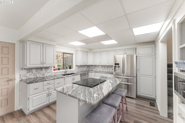 kitchen featuring appliances with stainless steel finishes, a center island, sink, and white cabinets