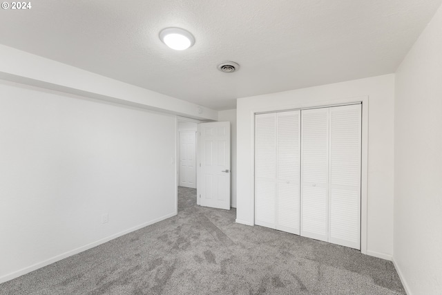 unfurnished bedroom featuring a closet, light carpet, and a textured ceiling