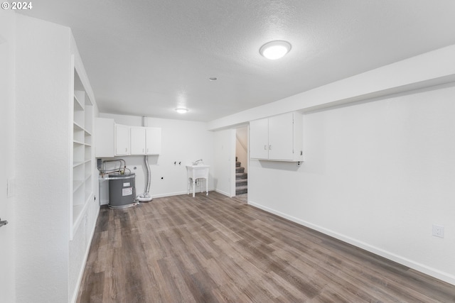 basement featuring water heater, sink, a textured ceiling, and light wood-type flooring