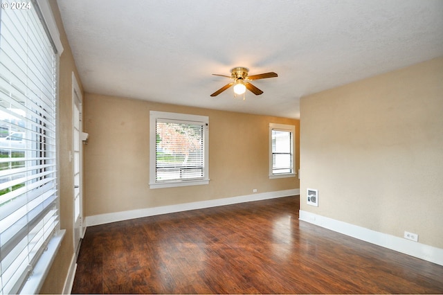 empty room featuring ceiling fan, dark wood-type flooring, and a textured ceiling