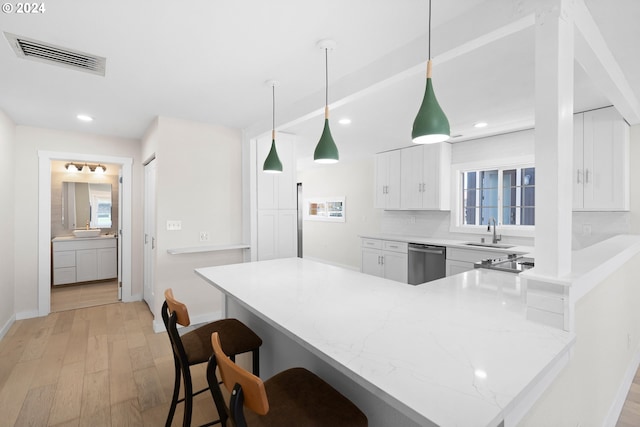 kitchen featuring a kitchen breakfast bar, light hardwood / wood-style flooring, pendant lighting, white cabinetry, and dishwasher