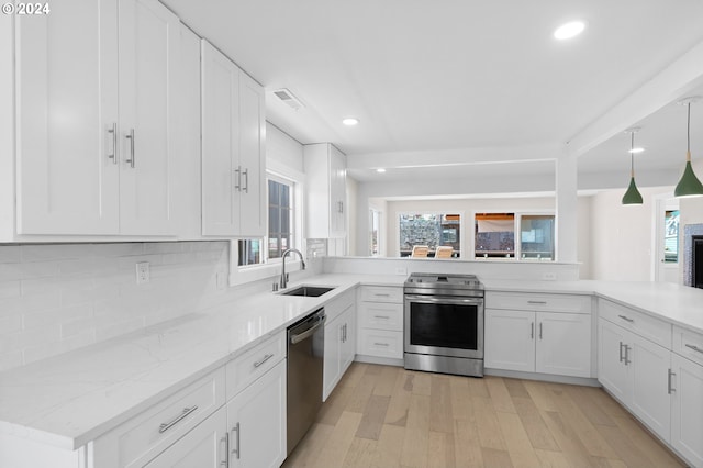 kitchen featuring appliances with stainless steel finishes, light hardwood / wood-style flooring, white cabinetry, sink, and hanging light fixtures