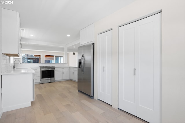 kitchen with sink, appliances with stainless steel finishes, light hardwood / wood-style flooring, decorative backsplash, and white cabinetry