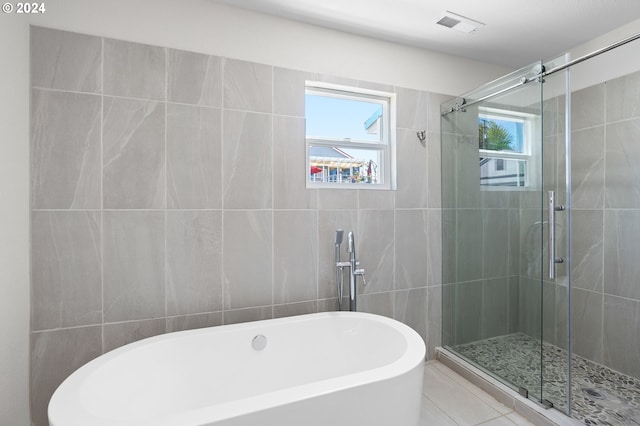 bathroom featuring plus walk in shower, tile walls, and tile patterned floors