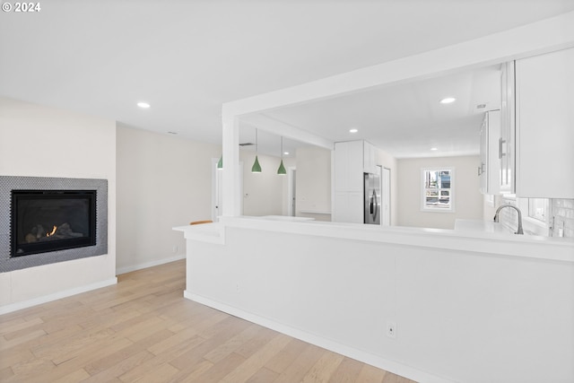 kitchen with white cabinets, decorative light fixtures, light hardwood / wood-style floors, and stainless steel refrigerator with ice dispenser